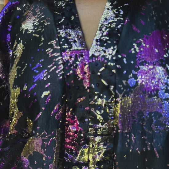 Model wearing an oversized brocade boubou with crystal beads in a colorful boutique. Elegant loose fit for sizes S to 3XL, recommended for heights 5'6" and taller.