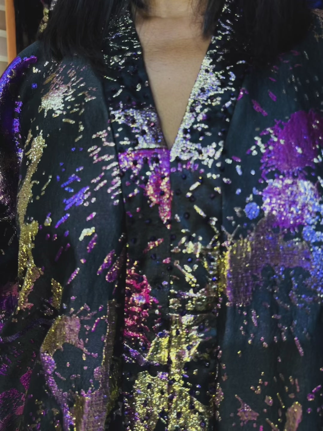 Model wearing an oversized brocade boubou with crystal beads in a colorful boutique. Elegant loose fit for sizes S to 3XL, recommended for heights 5'6" and taller.
