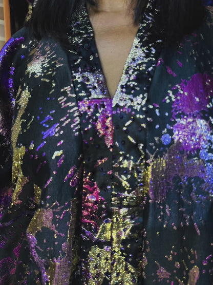 Model wearing an oversized brocade boubou with crystal beads in a colorful boutique. Elegant loose fit for sizes S to 3XL, recommended for heights 5'6" and taller.